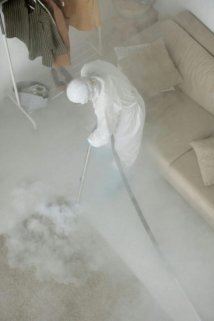 Person Wearing Protective Clothing Spraying Smoke on the Floor